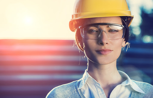 Une femme contremaître avec un casque et des lunettes de protection regarde le spectateur