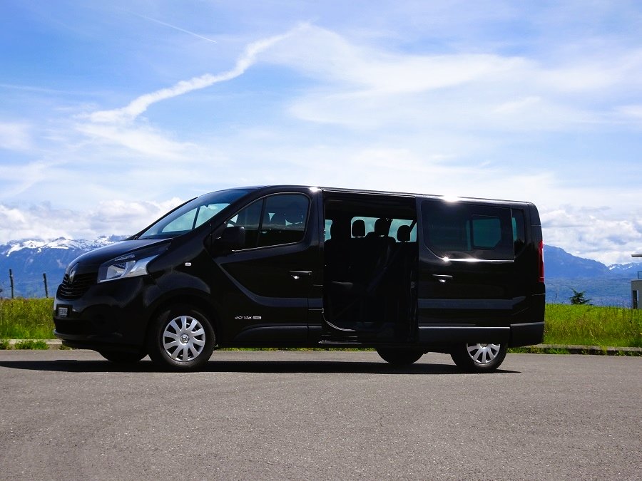 Un minimus 9 places renault trafic noir d'Exel Location avec en arrière plan un ciel bleu et des montagnes enneigées Location de minibus à Lausanne de 9 à 17 places